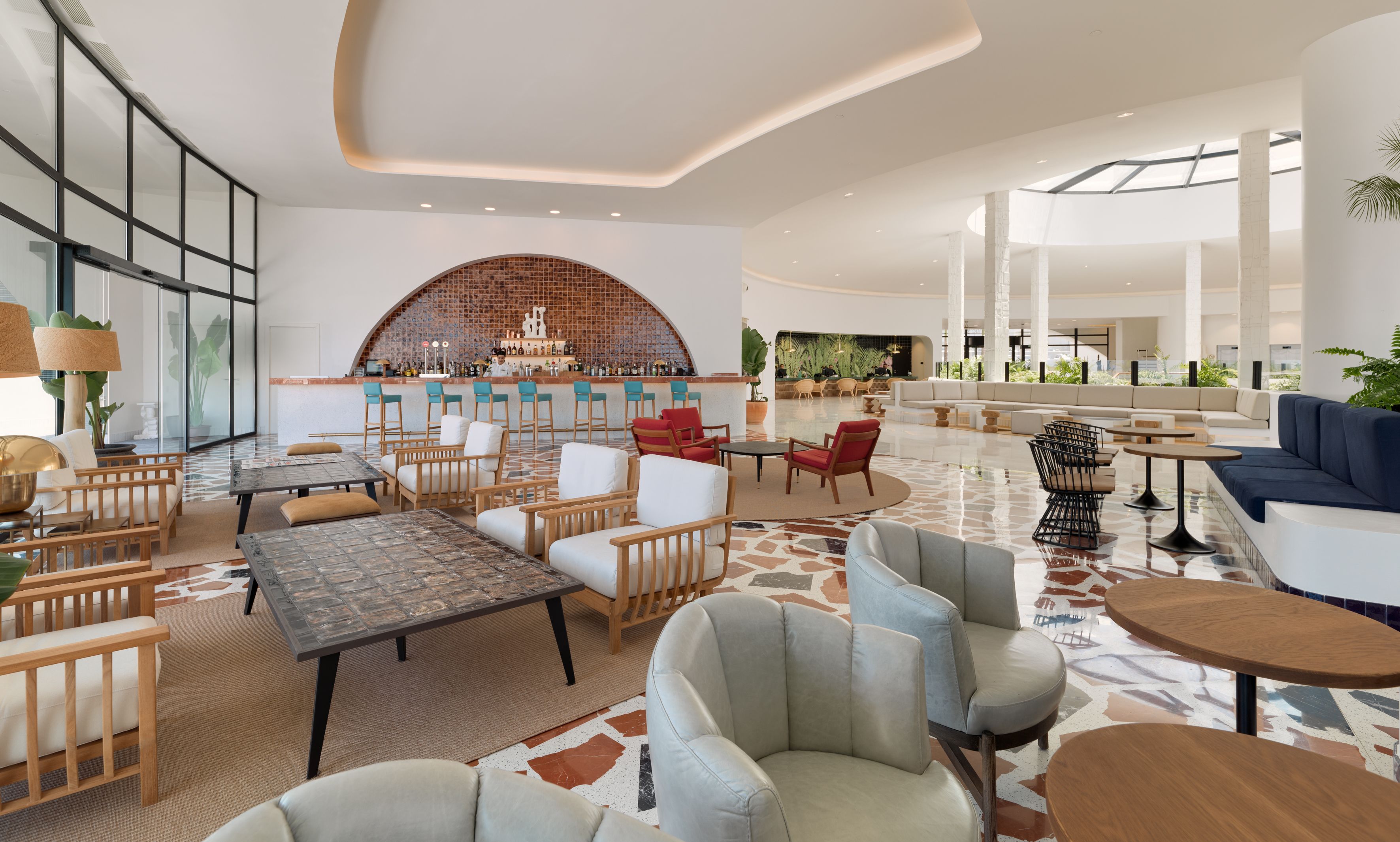 Een ruime lobby met een bar, zitgedeelte en een groot raam dat voor natuurlijk licht zorgt.