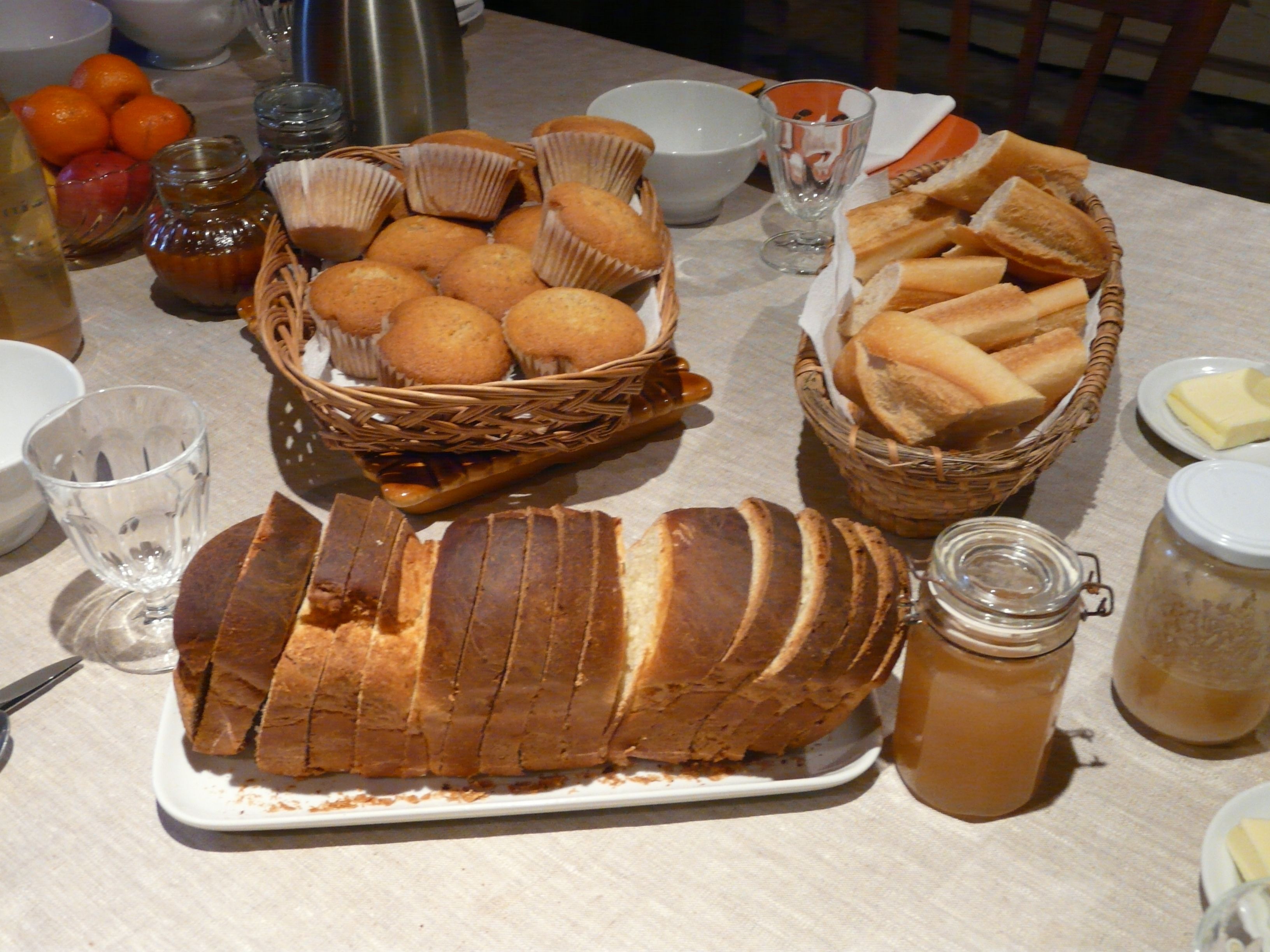 A table with various food items including bread, muffins, and a loaf of bread.
