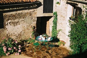 Um edifício rústico de pedra com um pequeno espaço ao ar livre, com uma mesa e cadeiras.