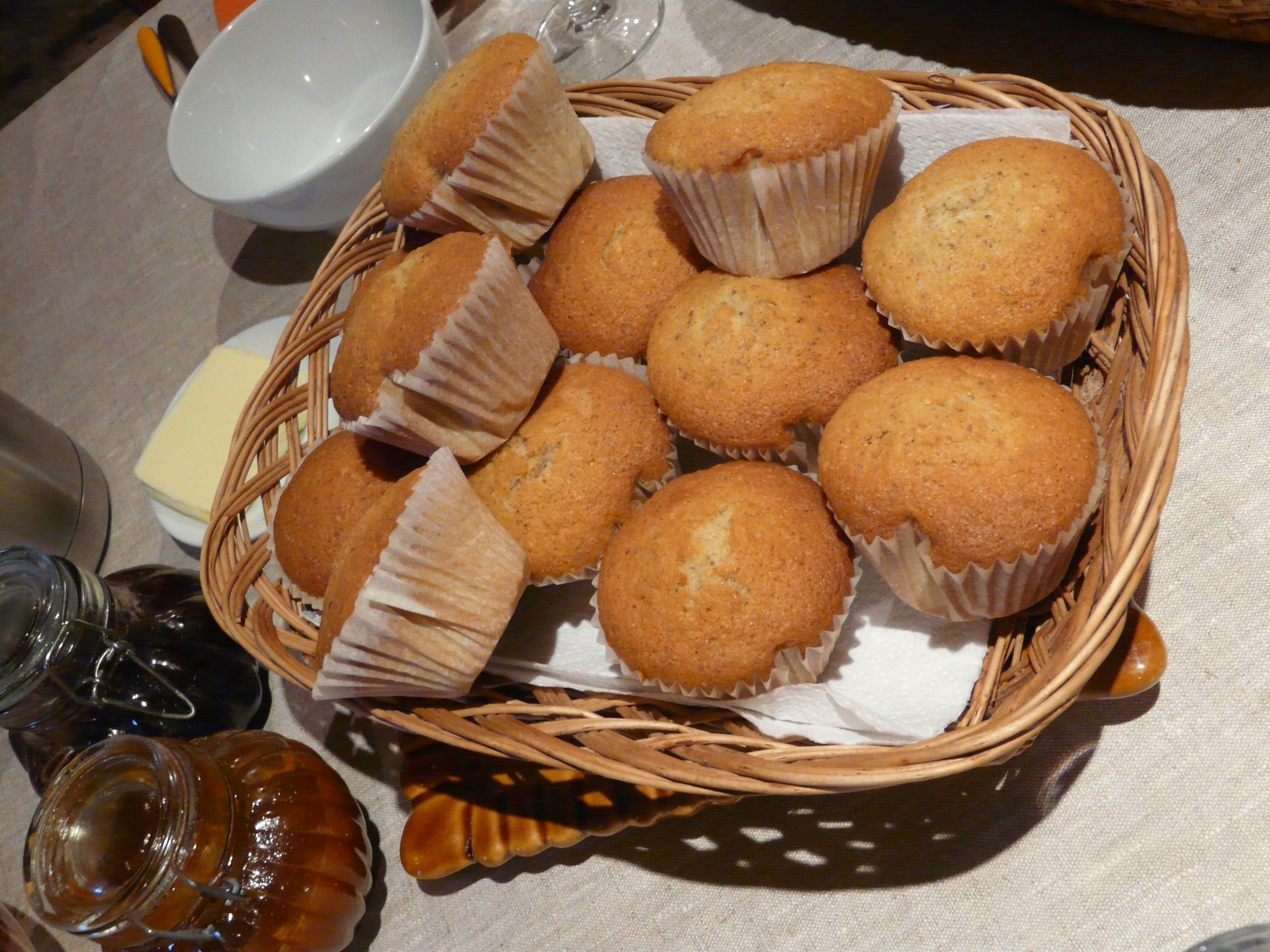 Una cesta de muffins sobre una mesa con mantel blanco.