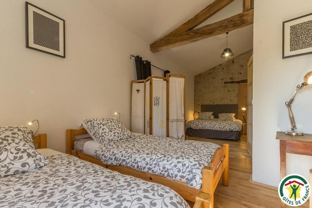 Un dormitorio con dos camas, vigas de madera, un escritorio pequeño y una mesita de noche.
