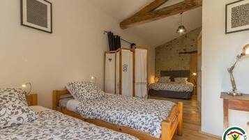 Un dormitorio con dos camas, vigas de madera, un escritorio pequeño y una mesita de noche.