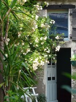 Um edifício rústico com uma porta branca e uma janela com persianas.