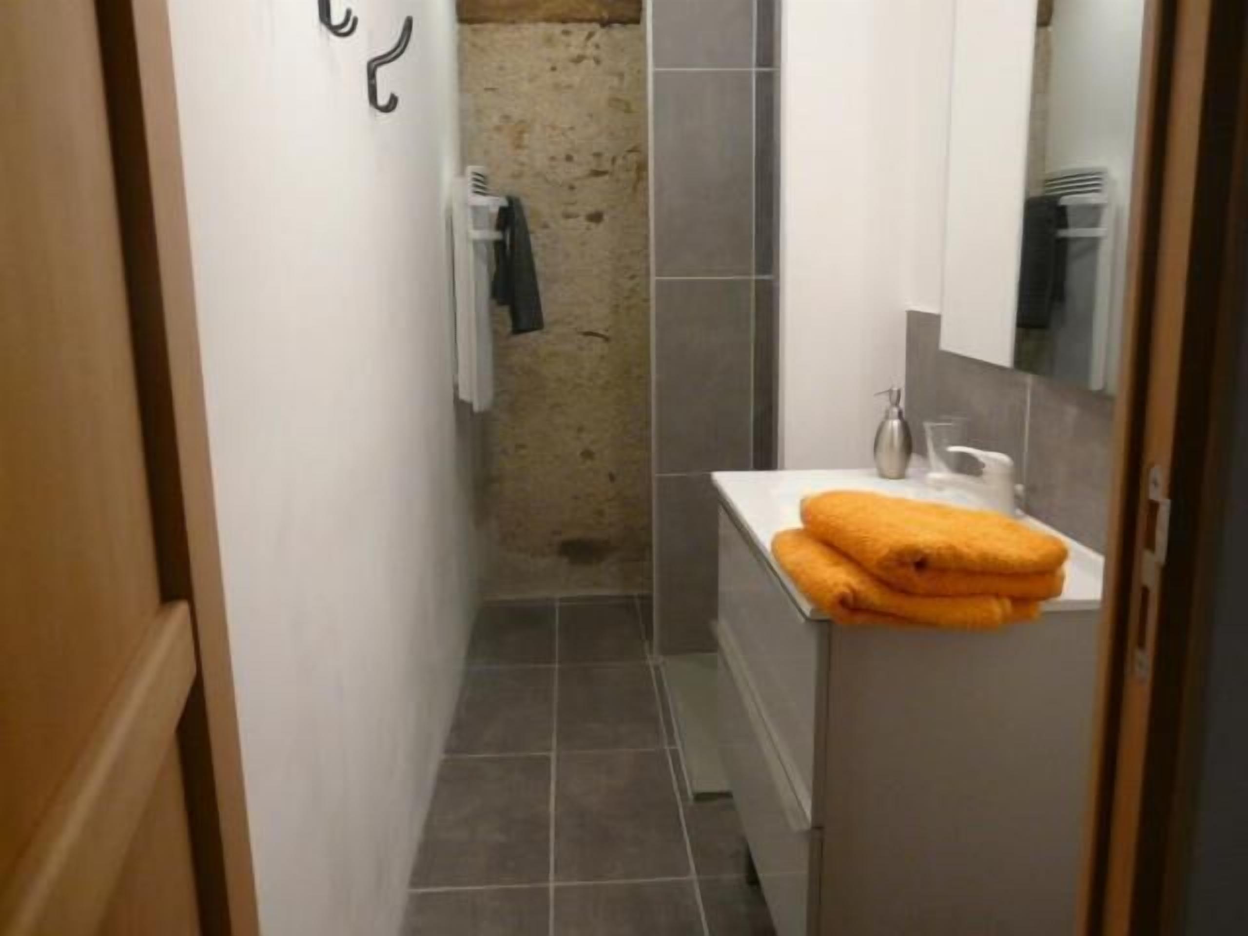 Een kleine badkamer met een wit wastafel, een spiegel en een handdoekrek.