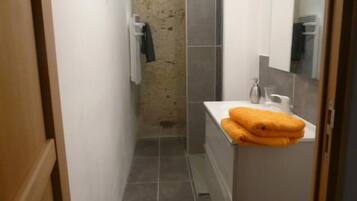 Een kleine badkamer met een wit wastafel, een spiegel en een handdoekrek.