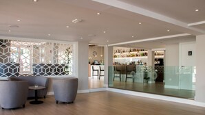 Ein modernes Interieur mit Bar, Sitzgelegenheiten und einer Trennwand aus Glas sowie einer geometrisch gestalteten Wand.