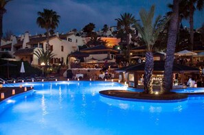 A swimming pool with lounge chairs and umbrellas, surrounded by palm trees and buildings. - La Quinta at La Manga Club (Cartagena)