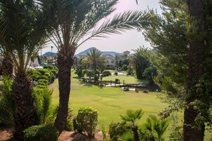 A well-maintained golf course with palm trees and manicured lawns, surrounded by buildings in the background.