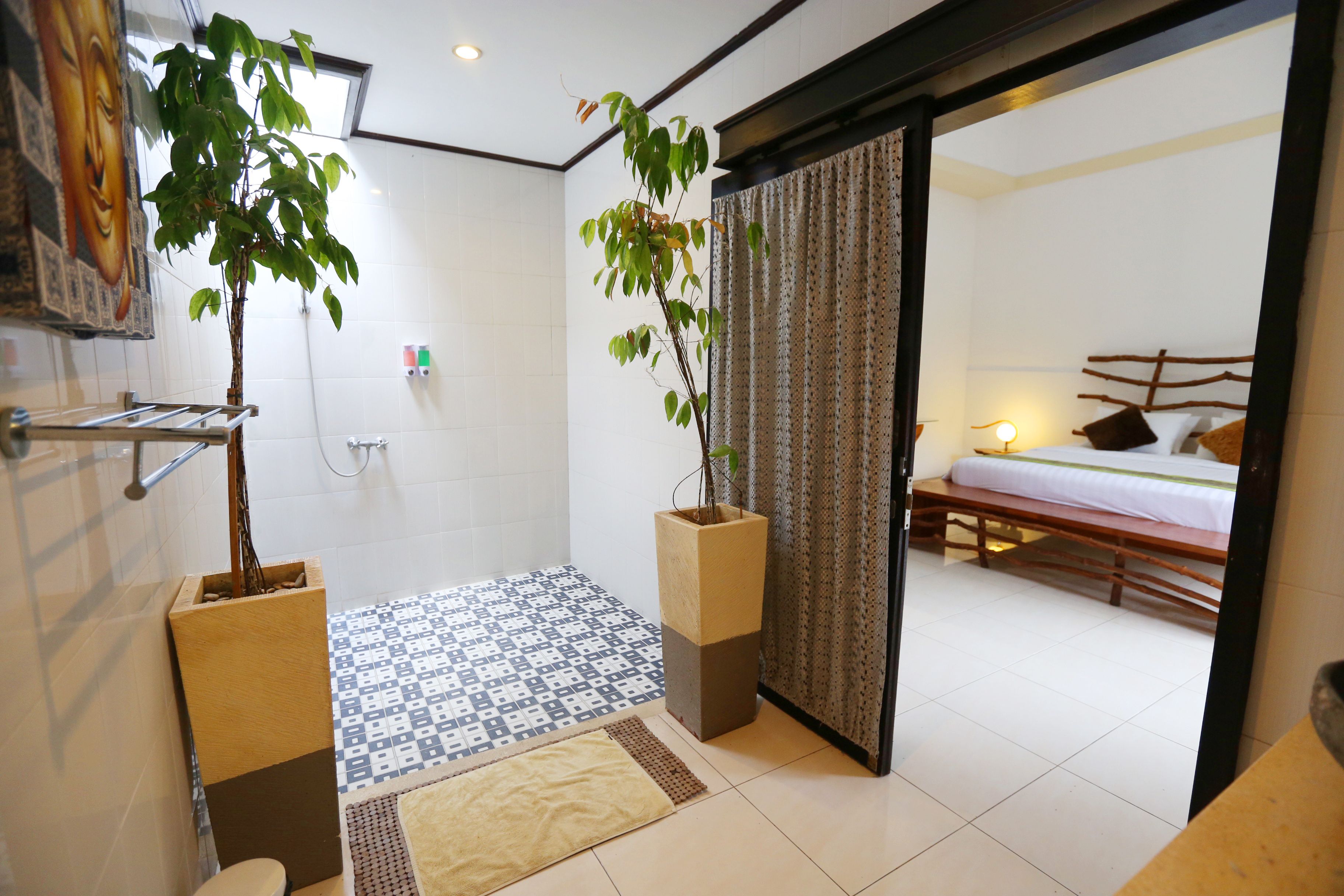 A modern bathroom with a shower, toilet, and sink. There are two potted plants and a patterned floor.