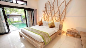 Un dormitorio con una cama de madera, vista a una piscina y una pared decorada con ramas.