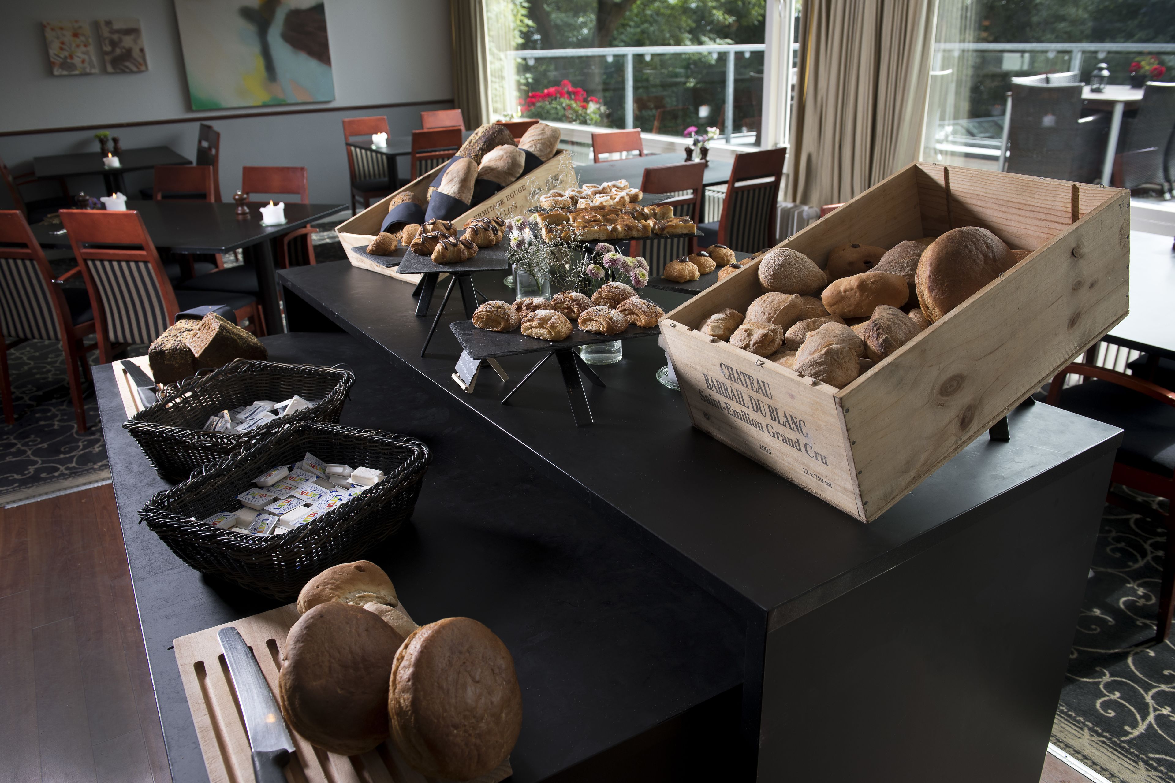 Una mesa de bufé con diversos productos horneados y cestas de pan.