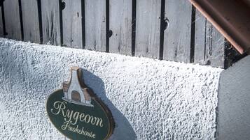 A wooden sign with the text "Rygeown Smokehouse" mounted on a white textured wall.