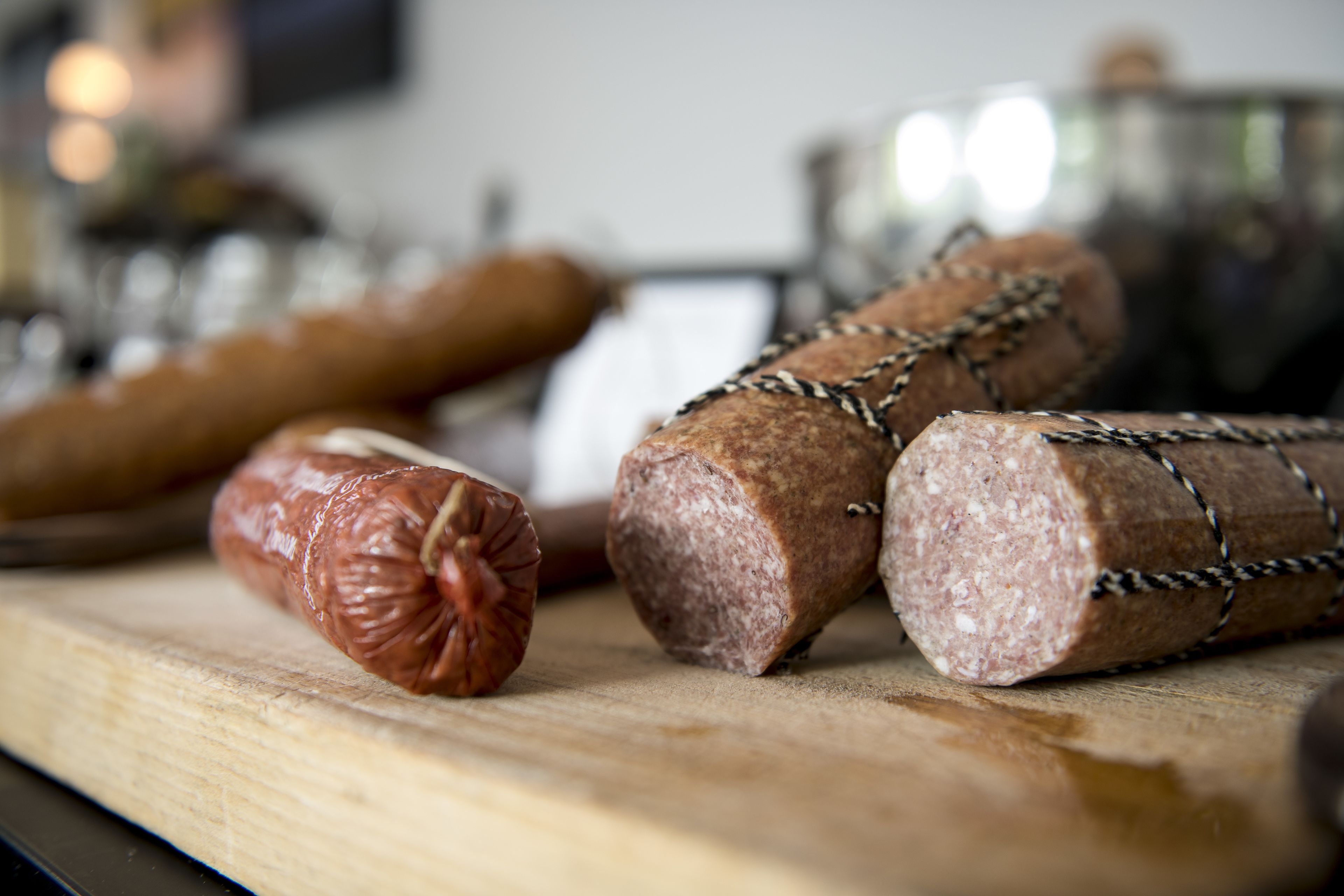 A variety of sausages on a wooden cutting board.
