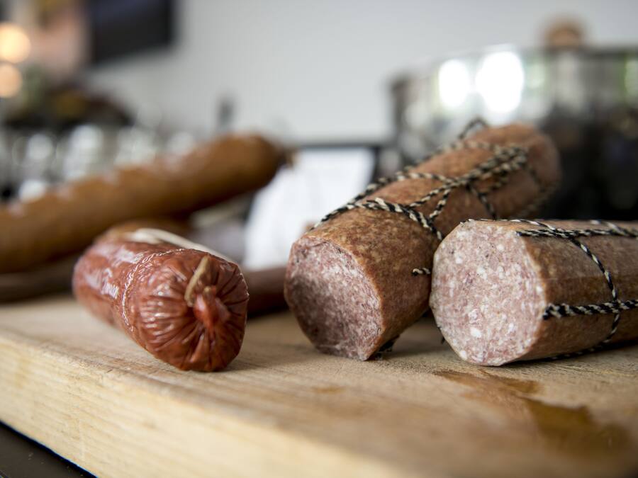 A variety of sausages on a wooden cutting board.