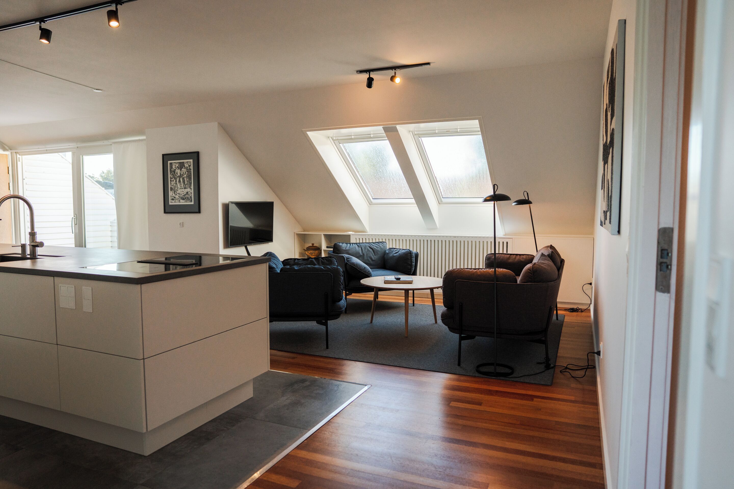 A modern kitchen with a central island, a dining area with a round table, and a cozy seating arrangement.