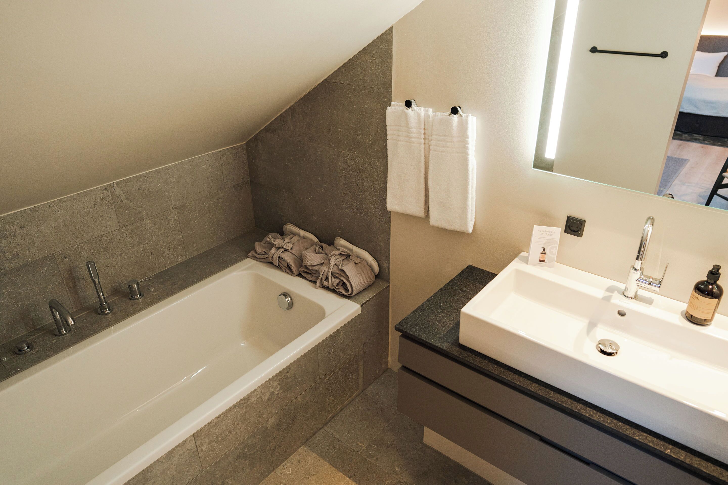 A modern bathroom with a bathtub, a sink, and a mirror.