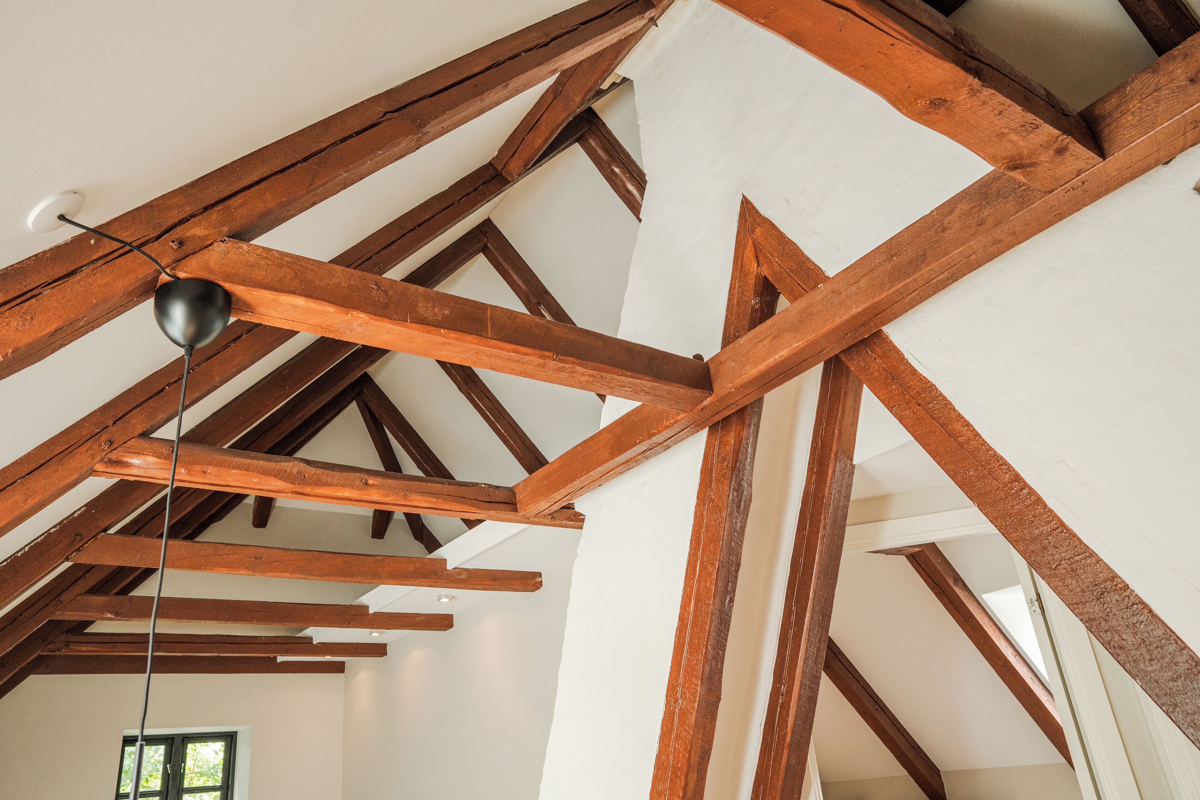 Ein Zimmer mit freiliegenden Holzbalken und einer hängenden Leuchte.