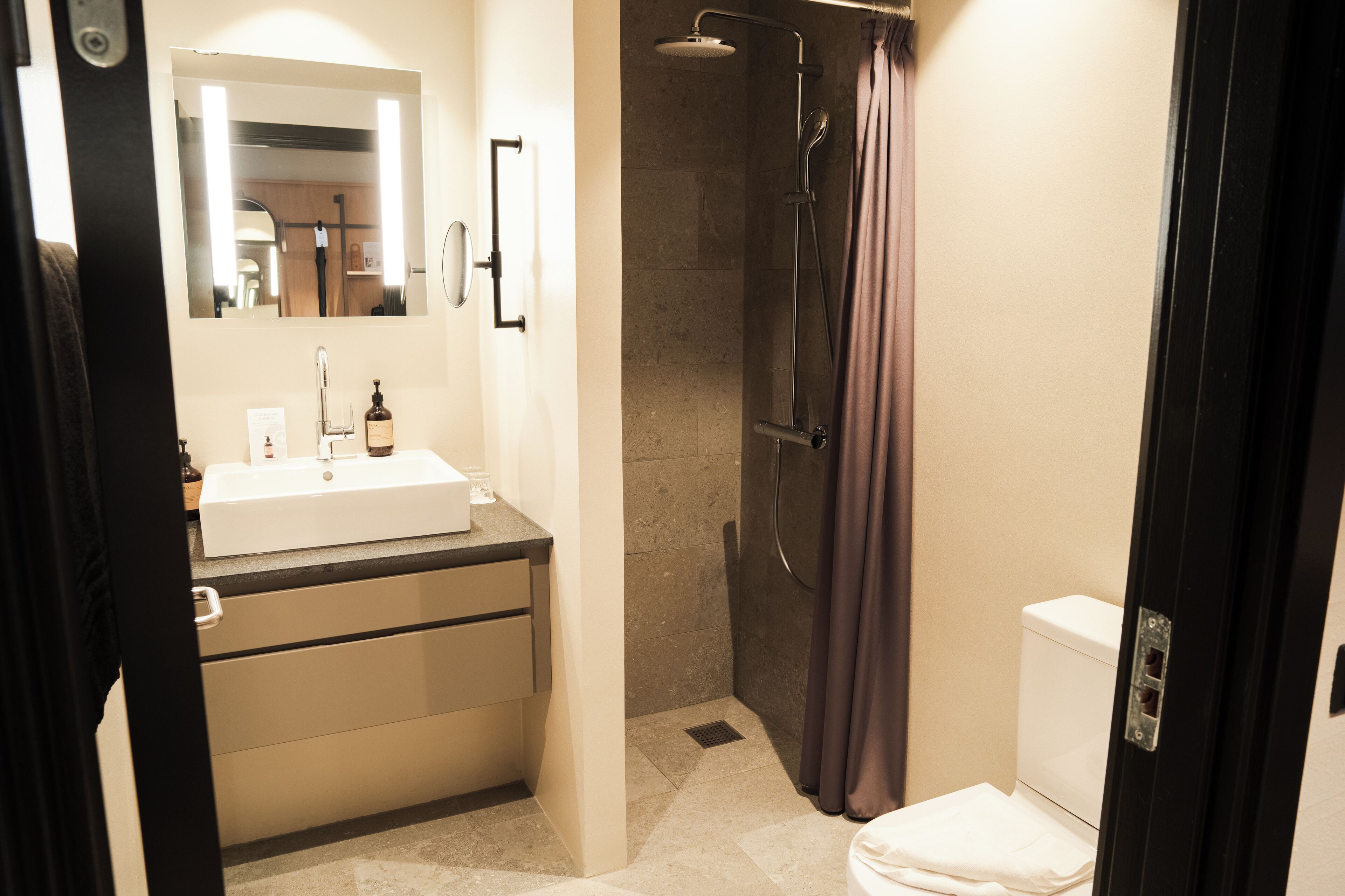 A bathroom with a sink, mirror, shower, and toilet.