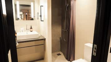 A bathroom with a sink, mirror, shower, and toilet.
