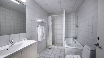 A modern bathroom with a sink, mirror, shower, and toilet.