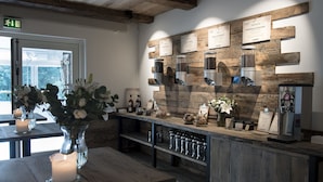 Een rustiek interieur met een houten toonbank, koffieapparaten en een vaas met bloemen.