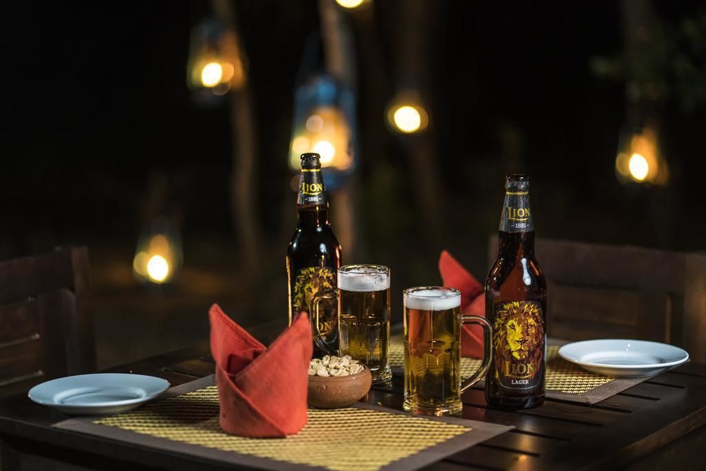 A table set for two with two beer bottles, two glasses, a bowl of snacks, and a red napkin.