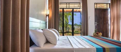 Ein Hotelzimmer mit einem Bett, Vorhängen, einem Fenster mit Blick und einer Tür.