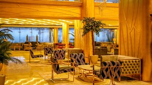 A spacious lobby with modern furniture, a large plant, and a chandelier. - Mirage Bab Al Bahr Hotel (Dhadnah)