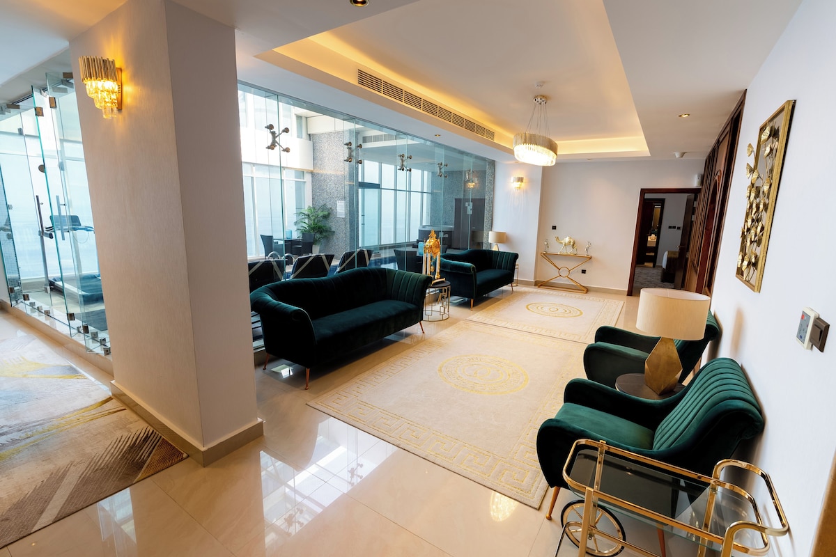 A spacious lobby with modern furniture, a glass wall, and a chandelier.