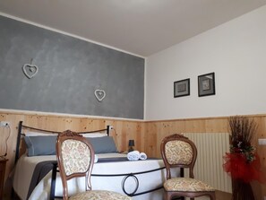A bedroom with a bed, two chairs, a dresser, and a radiator. - B&B Il Cardellino (Porano)