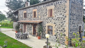 A stone building with a tiled roof, a patio with a table and chairs, and potted plants. - B&B Il Cardellino (Porano)