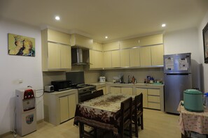 A compact kitchen with a dining table, a refrigerator, a water dispenser, and a microwave. - Pi Home Baciro (Yogyakarta)