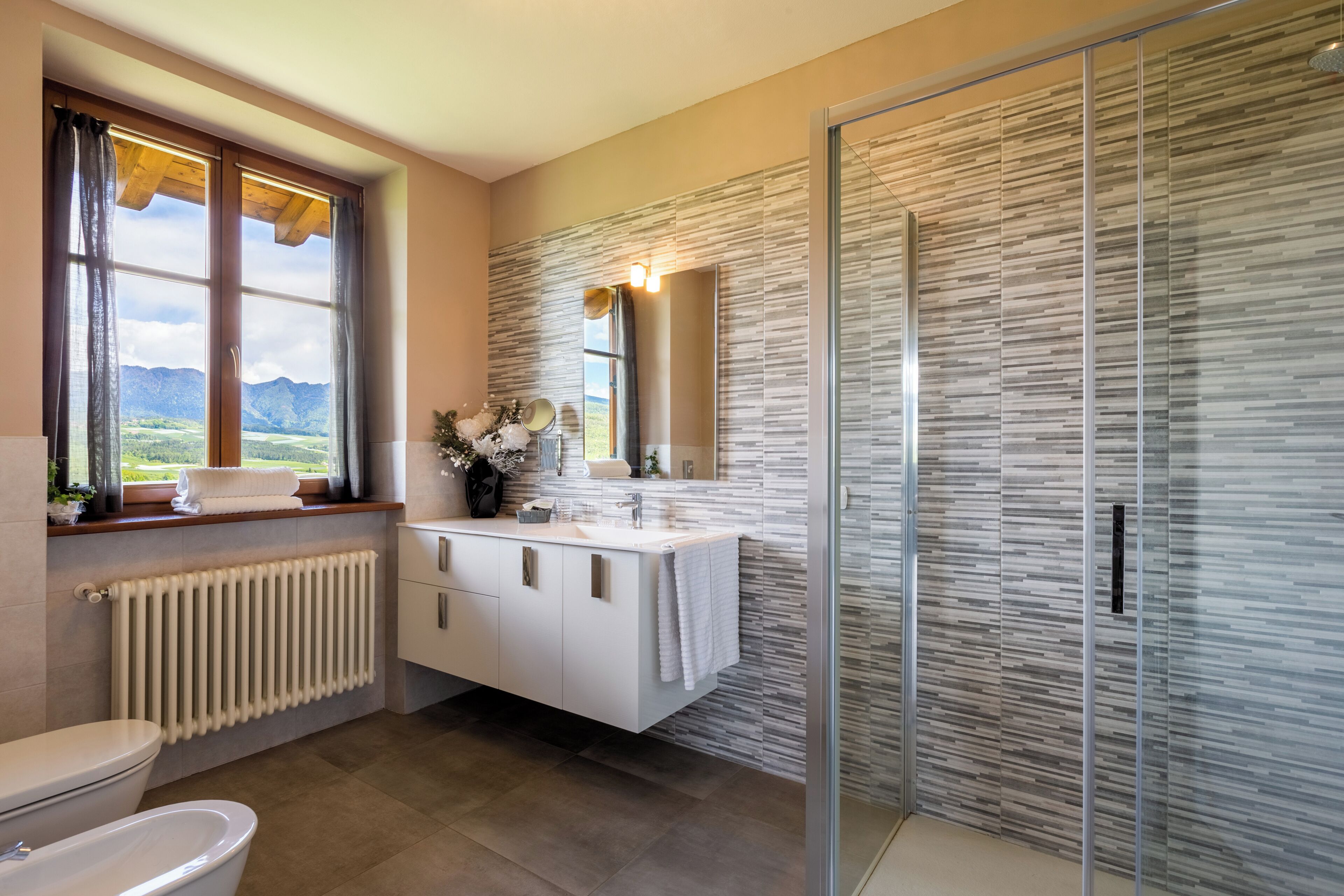 Un baño con inodoro, lavabo con espejo, ducha y ventana con cortinas.