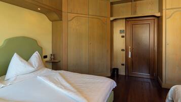 A hotel room with a large bed, wooden wardrobe, and a door.