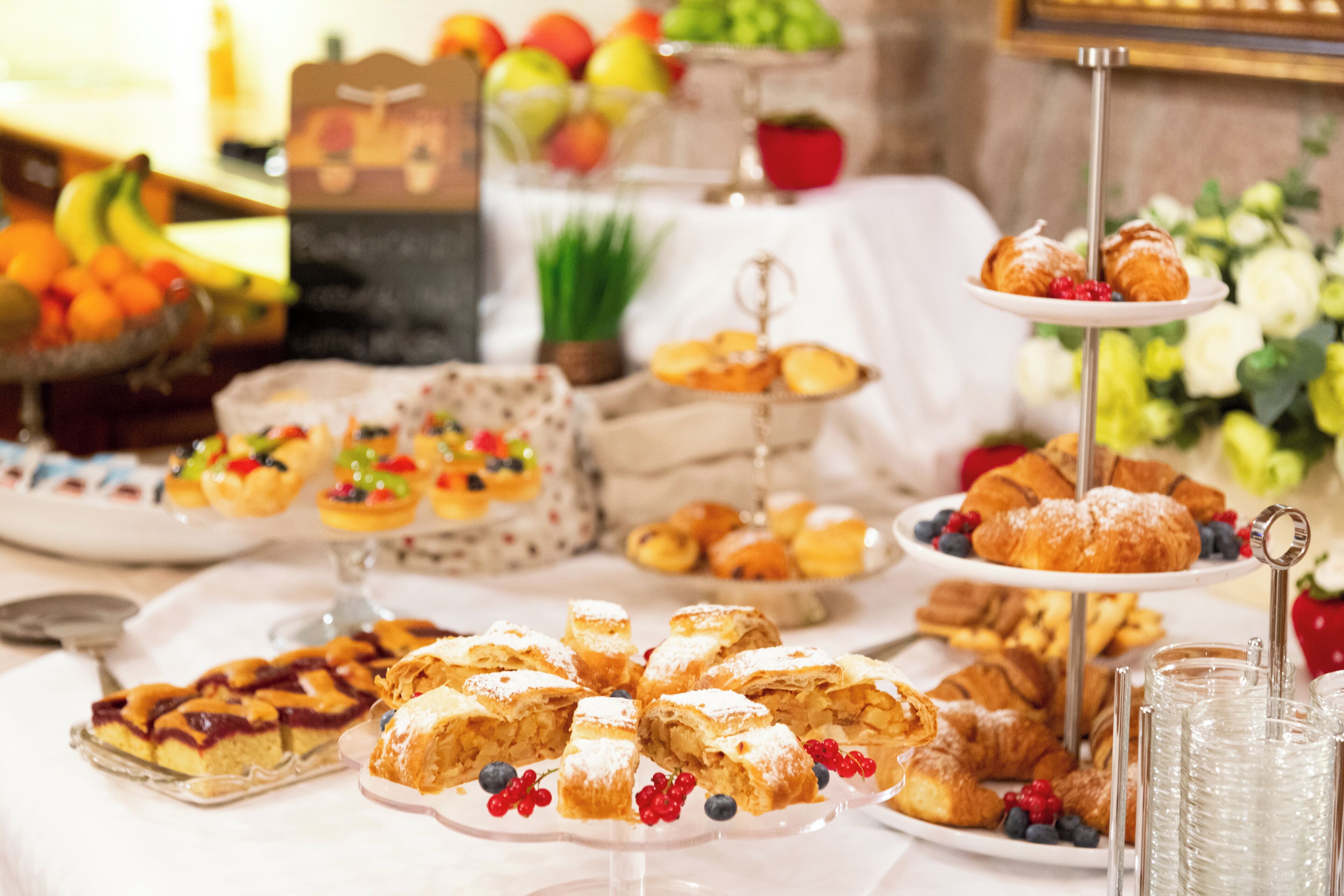 A buffet table with various pastries, fruits, and a three-tiered stand with desserts.