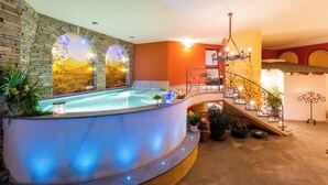 A spa area with a hot tub, a stone wall, and a staircase. - Relais Villa Quercia (Ville d'Anaunia)