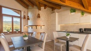 A modern kitchen with white cabinets, a dining area with a table and chairs, and a view of the outdoors. - Relais Villa Quercia (Ville d'Anaunia)