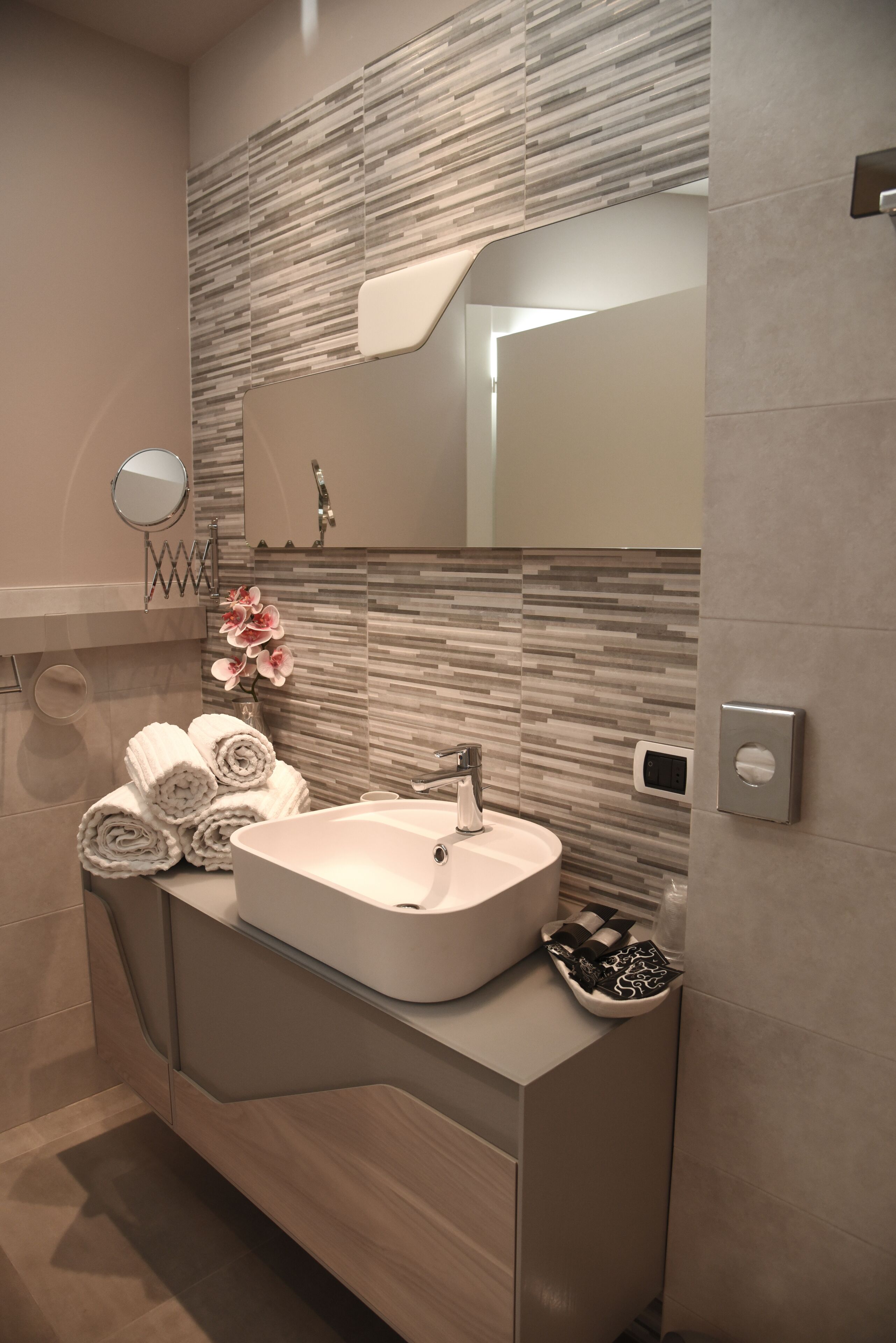 A modern bathroom with a large mirror, a sink, and a towel rack.