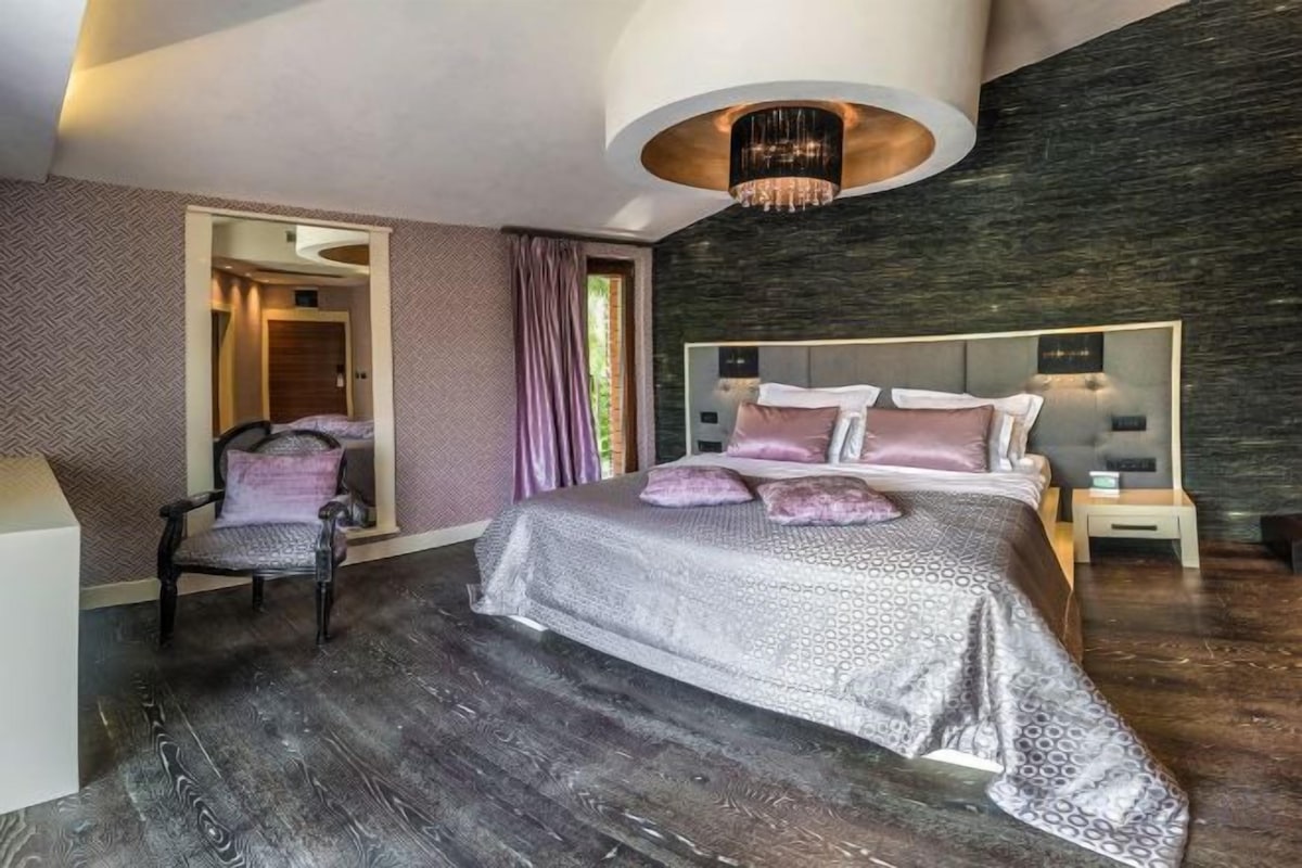 A modern bedroom with a large bed, a chair, and a nightstand.