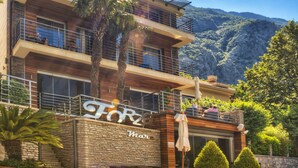A modern building with a balcony, a sign that reads "FORZ", and a mountainous backdrop. - Forza Mare (Kotor)