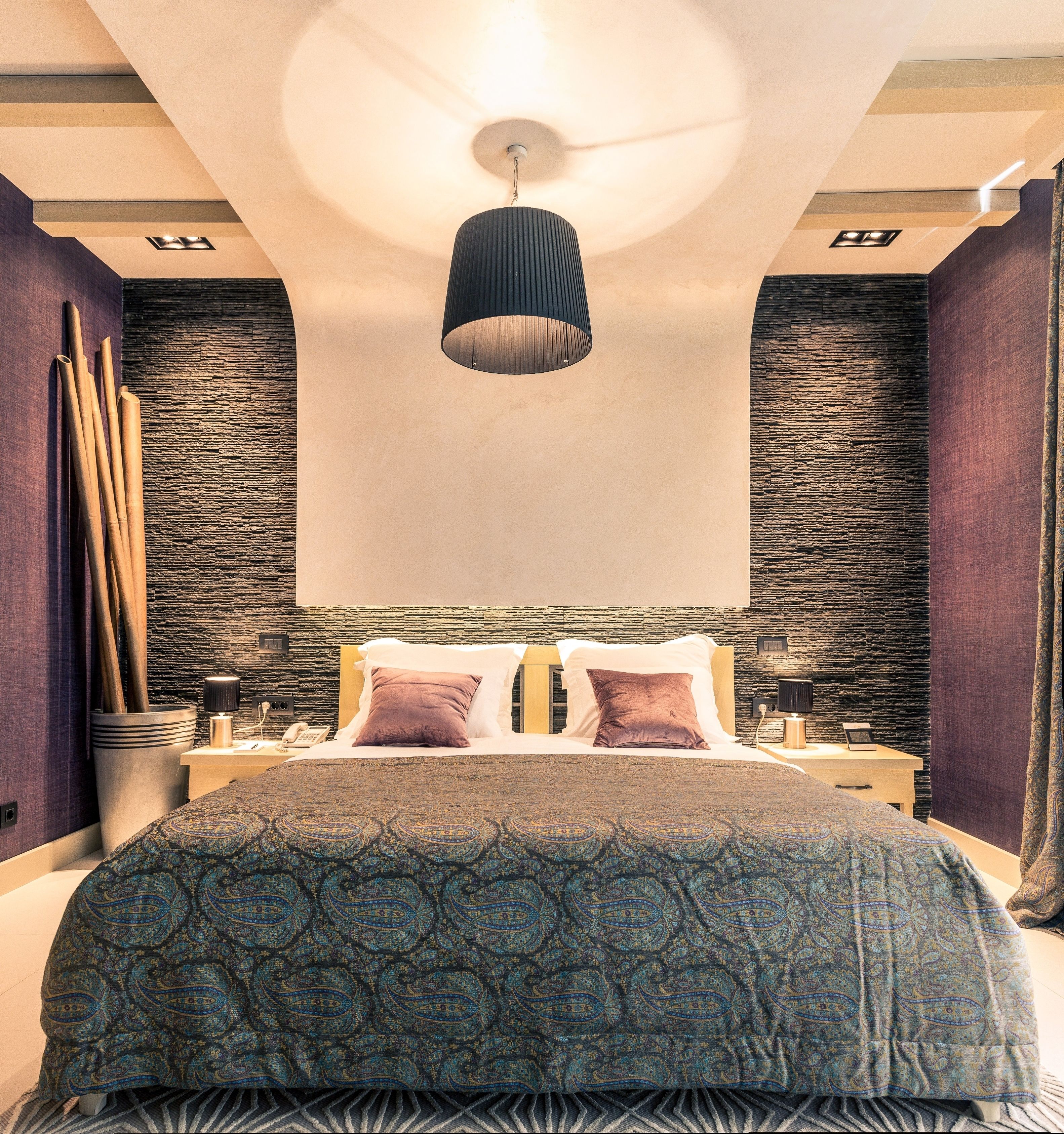 Un dormitorio moderno con una cama grande, una lámpara colgante y una pared texturizada.