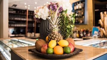 Una ciotola di frutta con ananas, mele, arance e lime su un bancone di legno.