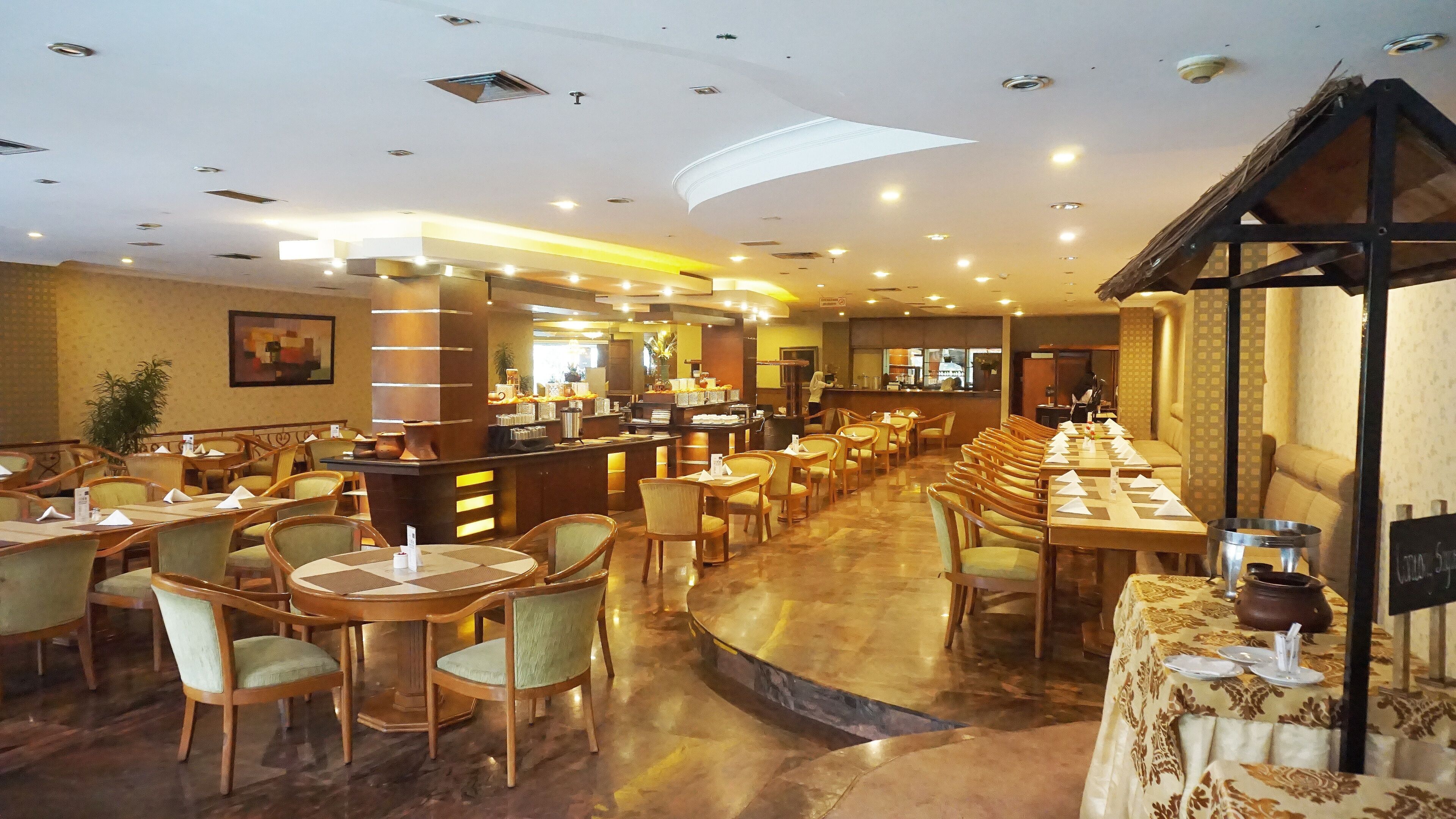 Un restaurante amplio con varias áreas de comedor, una barra y una barra alta. Las mesas están dispuestas con servilletas y cubiertos blancos.