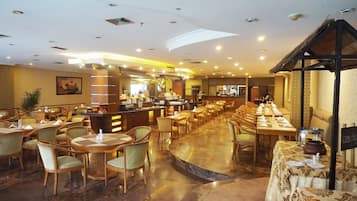 Un restaurante amplio con varias áreas de comedor, una barra y una barra alta. Las mesas están dispuestas con servilletas y cubiertos blancos.