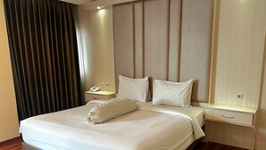 Una habitación de hotel moderna con una cama grande, una mesita de noche con un teléfono y una lámpara.