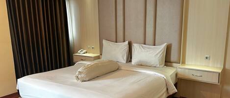 Una habitación de hotel moderna con una cama grande, una mesita de noche con un teléfono y una lámpara.