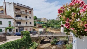 A residential area with a narrow stream, a bridge, and buildings with balconies. - Hotel La Palmera (Valverde del Fresno)