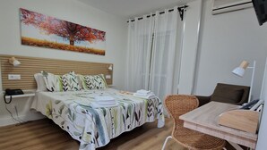 A neatly arranged bedroom with a bed, a small table, and a chair. - Hotel La Palmera (Valverde del Fresno)