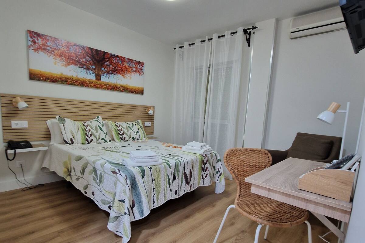Une chambre à coucher bien rangée, avec un lit, une petite table et une chaise.