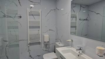 A modern bathroom with a white vanity, a large mirror, and a marble-patterned wall.